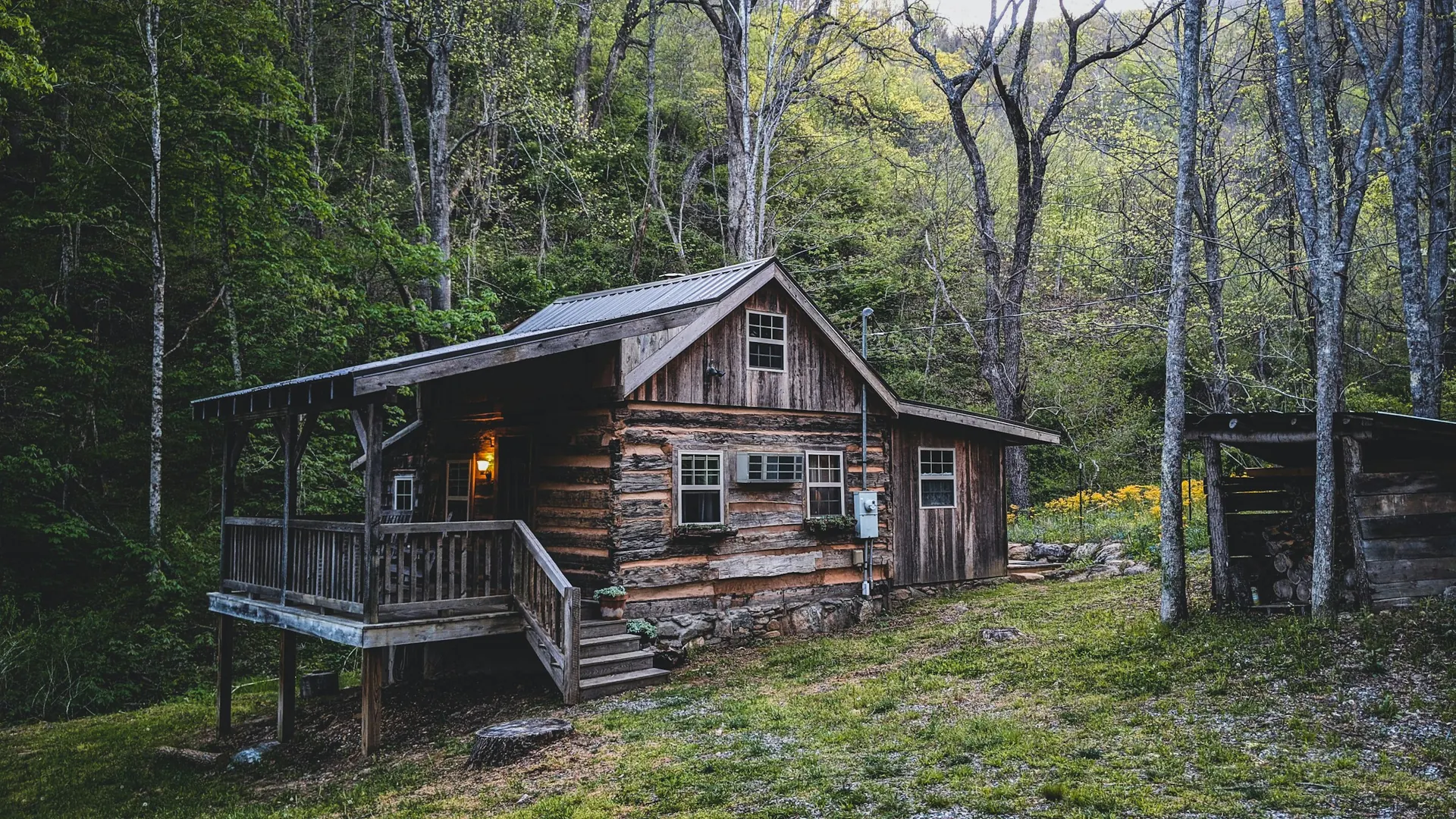 A weathered wood cabin with a covered porch in hardwood forest near Leicester, North Carolina